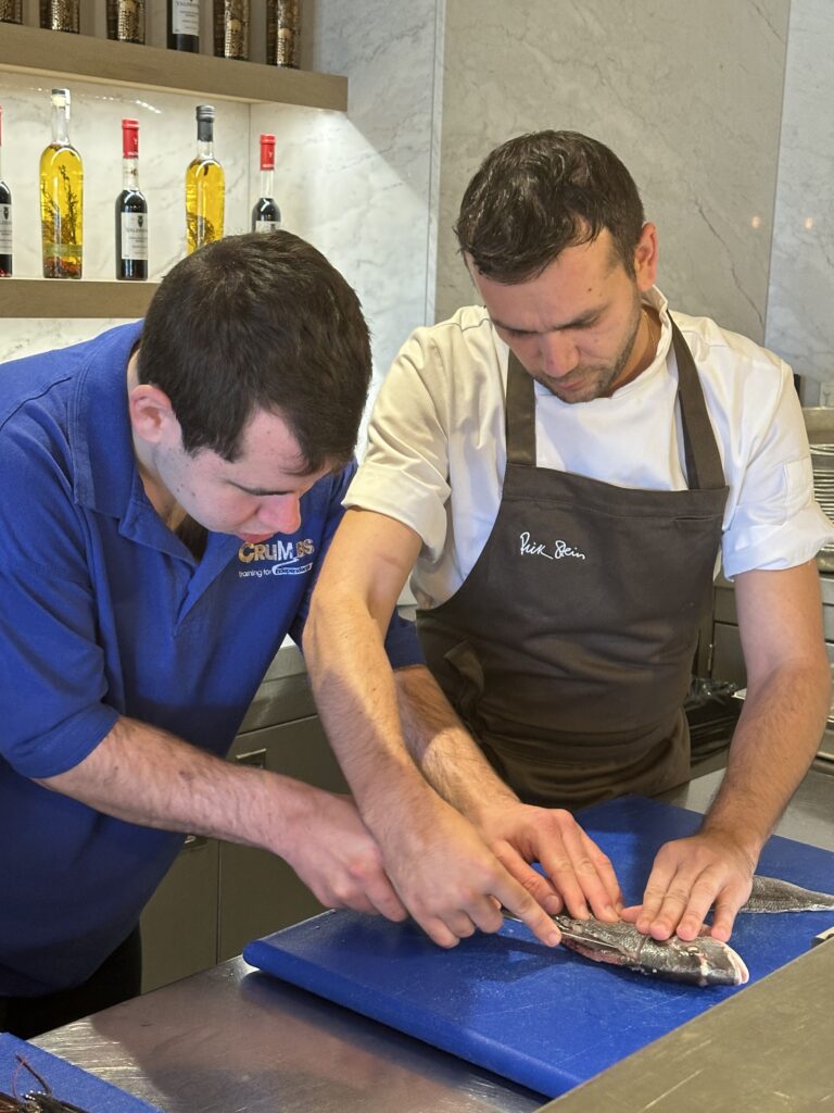 The CRUMBS Project's trainee James filleting fish with a chef Raz from Rick Stein Sandbanks restaurant
