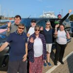 A group of trainees and staff stand smiling at the ferry port in Lymington