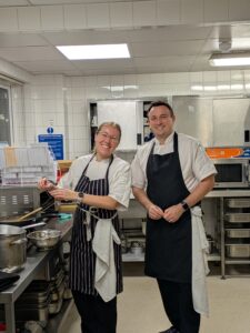A volunteer female chef and a male chef stand in the training kitchen at The CRUMBS Project training centre