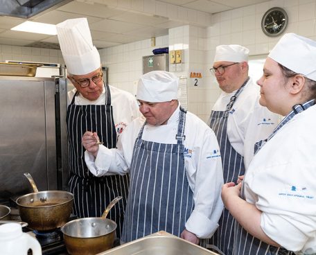 A group of trainees with a professional chef in the training kitchen.