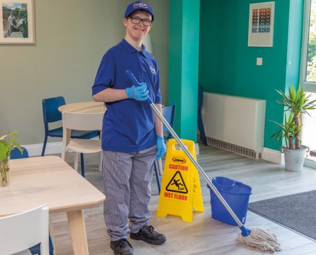 A trainee cleaning a floor