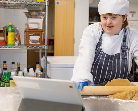A trainee in the bakery looking at a tablet