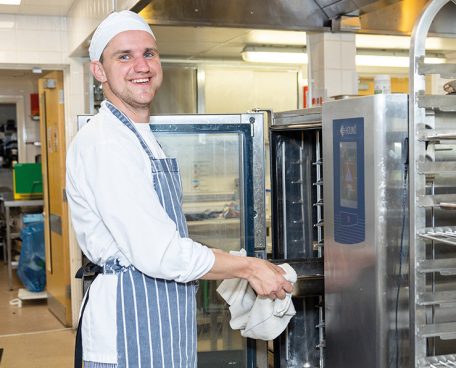 A trainee using an oven in the training kitchen