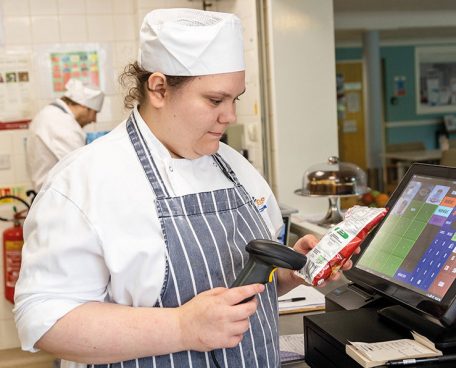 A trainee using a till in the training kitchen