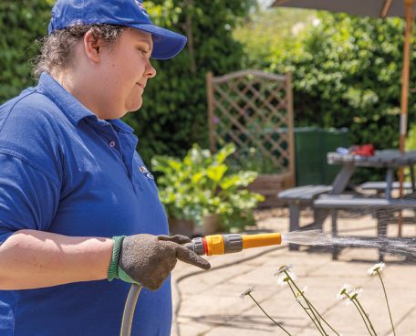 A trainee watering plants in the kitchen garden