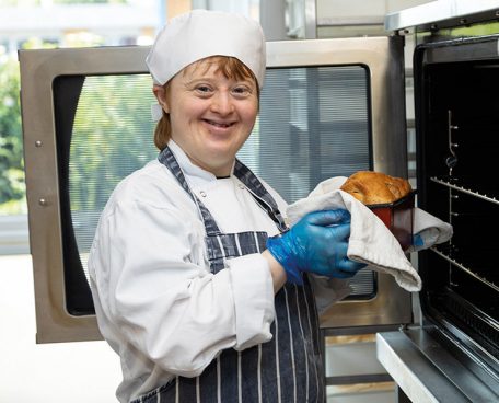 A trainee with a loaf of bread they have baked