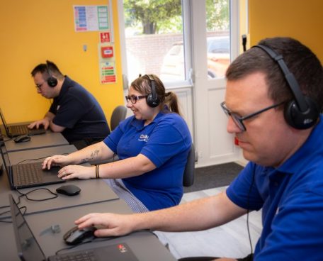 Trainees using laptops and headphones in the computer room